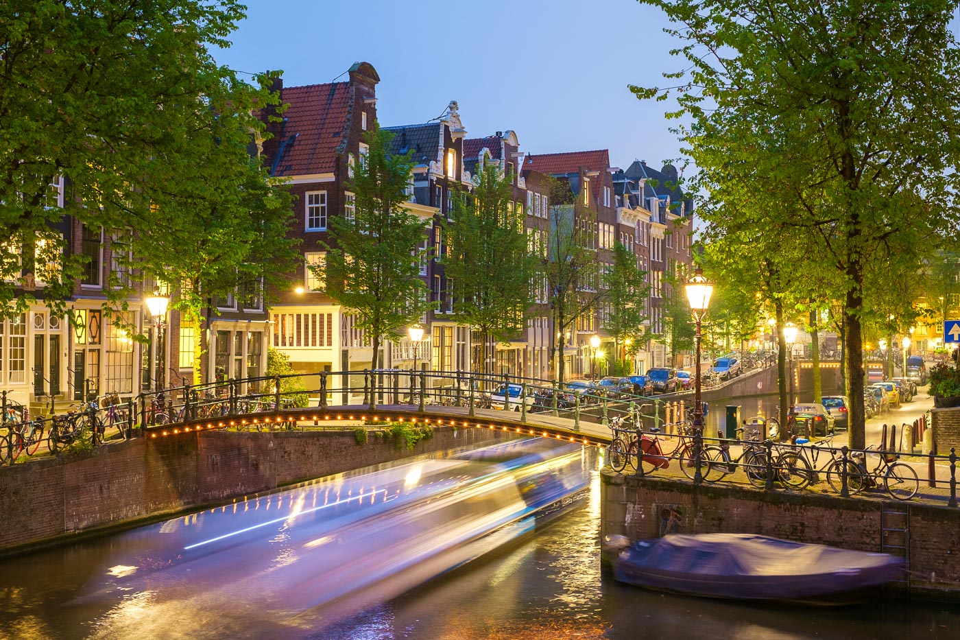 Canal boat passing under bridge on the Brouwersgracht in western Grachtengordel canal ring at dusk