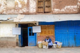 Woman selling bread on the street in front of small cafe, Cusco, Peru, South America