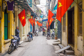 Alleyway decorated with red Vietnamese flags, Hanoi, Vietnam