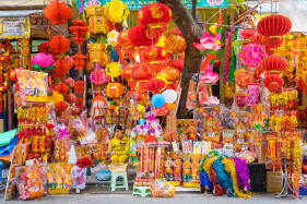 Woman surrounded by colorful lanterns and decorations during Tết (Vietnamese New Year), Hoàn Kiếm District, Old Quarter, Hanoi, Vietnam