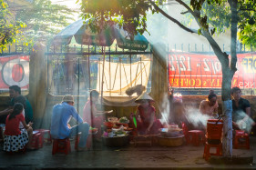 People eating at street food stall on the sidewalk in Hoi An, Quang Nam Province, Vietnam
