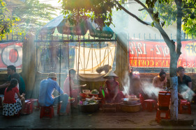People eating at street food stall on the sidewalk in Hoi An, Quang Nam Province, Vietnam