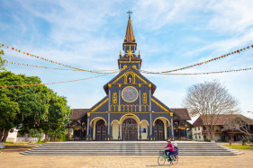 Childen ride a biycycle in front of Kon Tum Cathedral, also known as Wooden Church, Kon Tum, Kon Tum Province, Vietnam