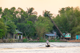A man paddles across the Cần Thơ River, a branch of the Mekong, Cần Thơ, Vietnam