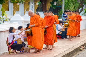 Buddhist novice monks recieve alms (Tak Bat) at dawn in front of Wat Sirimoungkhoun Sayaram temple, Luang Prabang, Louangphabang Province, Laos